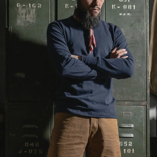 Henley Cotton Organic Long Sleeve T-Shirt worn by a man against vintage lockers, showcasing style and comfort.