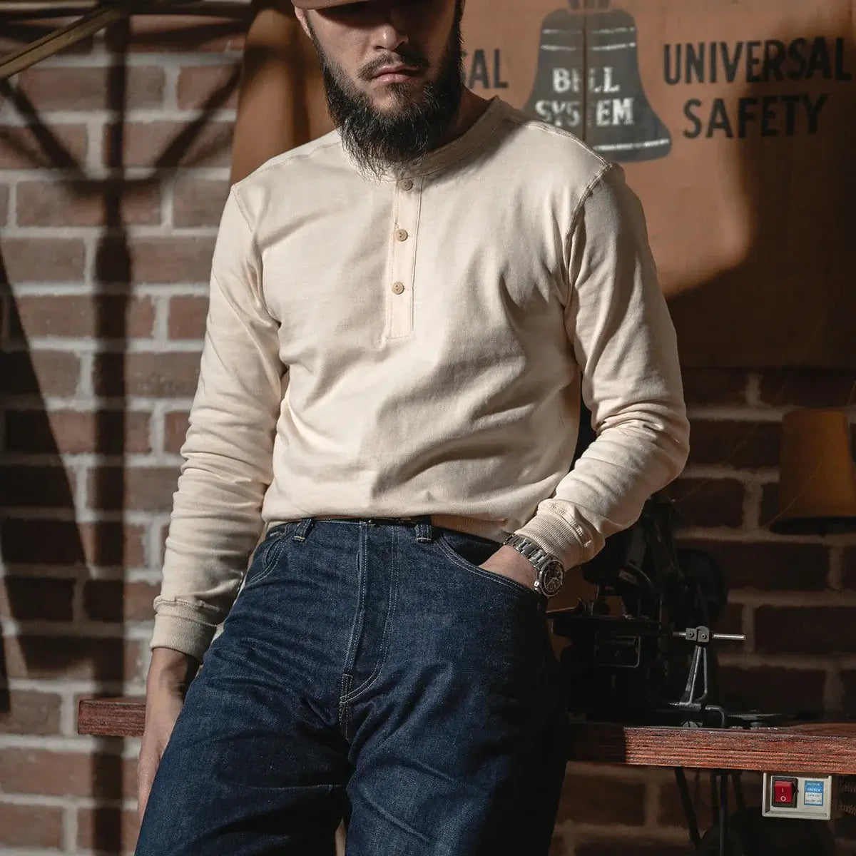 Henley Cotton Organic Long Sleeve T-Shirt displayed by a man in a stylish, vintage setting with brick background.